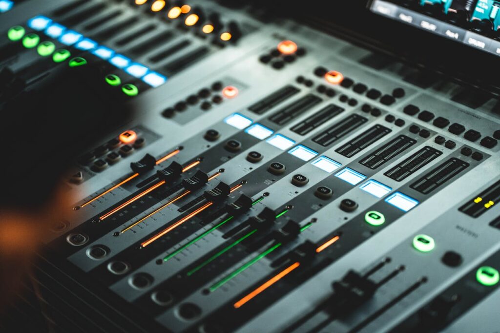 pexels-photo-3469712 Close-up of a professional audio mixing console with illuminated LED indicators in a music studio.